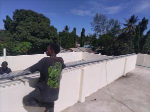 a man is leaning against a white wall at Mtomo vision in Mtwapa