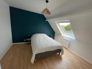 a bedroom with a bed with a blue wall and a window at La Guignicourtoise in Guignicourt