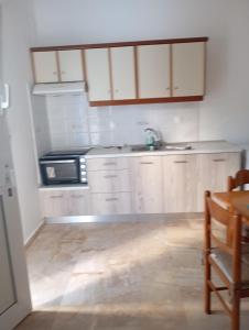 a kitchen with white cabinets and a wooden floor at Spacious Apartment Garden View Partial Seaview in Makry Gialos