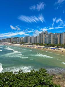 a beach with buildings and people in the water at Grand Hotel Guarujá - A sua Melhor Experiência Beira Mar na Praia! in Guarujá