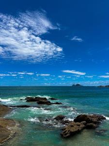 a view of the ocean with rocks in the water at Grand Hotel Guarujá - A sua Melhor Experiência Beira Mar na Praia! in Guarujá