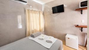 a bedroom with a bed with a tv on the wall at Perto da Meia Praia e do Píer com Cozinha Garagem Ar Wi-Fi e Enxoval - CASA OLINDA in Porto Belo