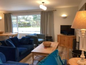 a living room with blue couches and a table at Tarn View in Winster