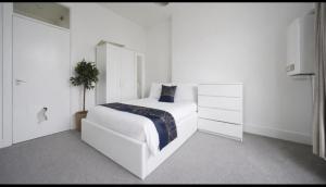 a white bedroom with a bed and a dresser at Comfortable 2-Bed Flat with Free Parking in Paisley
