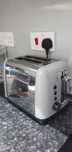 a white toaster sitting on a kitchen counter at Comfortable 2-Bed Flat with Free Parking in Paisley