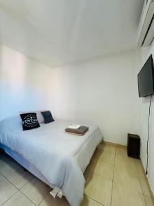 a white bedroom with a bed and a tv at Departamento Centrico Iguazu 2A in Puerto Iguazú
