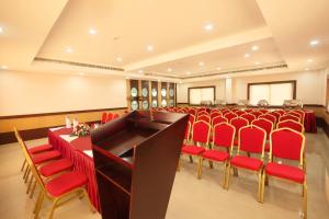a conference room with red chairs and a podium at Hotel Virad in Kottakkal