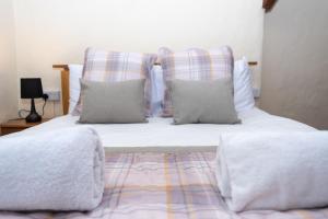 a bed with white sheets and pillows in a bedroom at The Stables - Old Mill Cottages in Ilfracombe