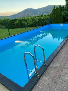 a swimming pool with blue water and mountains in the background at Dom lub apartamenty z widokiem na góry Wichrowe Wzgórza z basenem Brenna in Ustroń