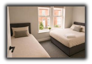 two beds in a room with two windows at The Red Lounge Rooms in Liverpool