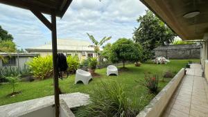 a yard with two white chairs in the grass at La Maison Du Bonheur in Capesterre-Belle-Eau