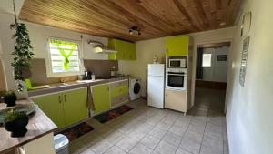 a kitchen with green cabinets and a white refrigerator at La Maison Du Bonheur in Capesterre-Belle-Eau
