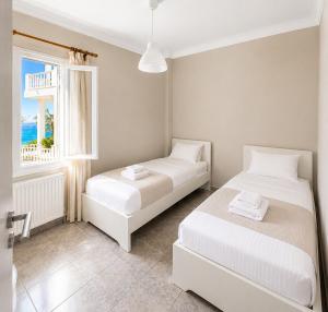 two beds in a room with a window at Araucaria Beachfront Residence in Finikas