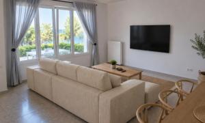 a living room with a couch and a television at Araucaria Beachfront Residence in Finikas