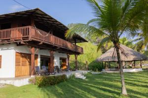 a house with a balcony and a palm tree at Mareselva Lodge in Acanti