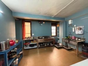 a large kitchen with blue walls and wooden floors at Laxman Homestay in Sarāhan