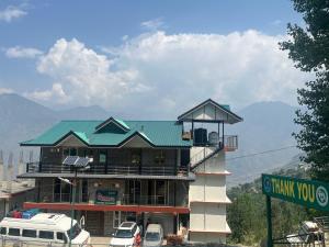 a building with a green roof with cars parked in front at Laxman Homestay in Sarāhan