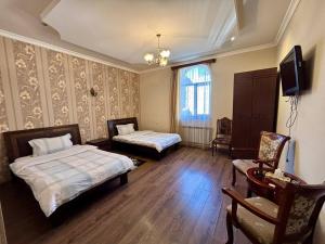 ein Schlafzimmer mit zwei Betten, einem Fernseher und einem Stuhl in der Unterkunft Christy Hotel in Goris