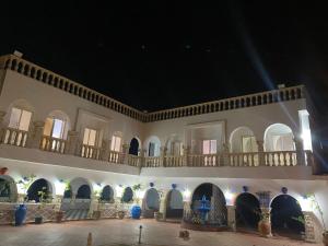 a building with a balcony and a courtyard at night at Villa pamplemousse in Banī ‘Aţāʼ
