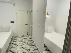 a small white room with two beds and a closet at Villa pamplemousse in Banī ‘Aţāʼ