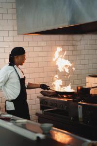 a woman in a kitchen with a stove with fire at SABAI Beach Hotel in Barú