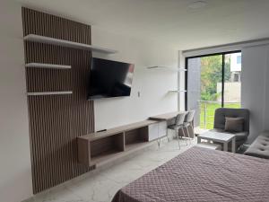 a bedroom with a bed and a tv on a wall at Hermosos Apartaestudios! in Florencia