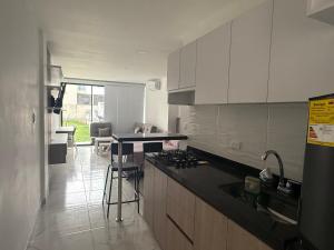 a kitchen with white cabinets and a black counter top at Hermosos Apartaestudios! in Florencia