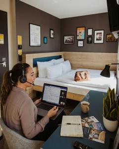 a woman with headphones and a laptop in a hotel room at Schulz Hotel Berlin Wall at the East Side Gallery in Berlin
