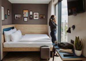 a woman talking on a cell phone in a bedroom at Schulz Hotel Berlin Wall at the East Side Gallery in Berlin