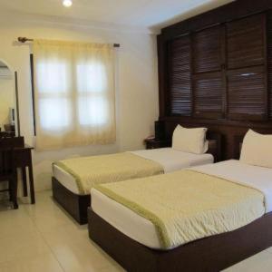 a bedroom with two beds and a desk and a window at Bautong Lodge in Chiang Mai