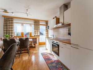 a kitchen with white cabinets and a dining room at Nussbaumer S in Niedernsill