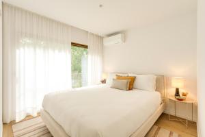 a white bedroom with a large bed and a window at Matosinhos in Matosinhos