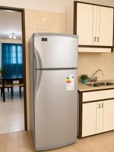a stainless steel refrigerator in a kitchen with a sink at Alto Belgrano II in Mendoza