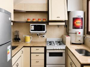 a small kitchen with a stove and a microwave at Alto Belgrano II in Mendoza