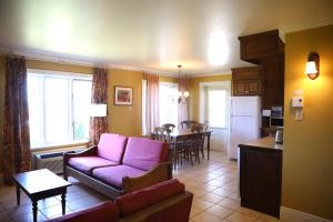 a living room with a purple couch and a kitchen at La Remontée Appartements Hôtel in La Malbaie