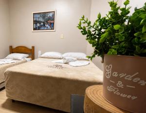 a room with two beds and a potted plant at Pousada Folhas de Outono in Canela