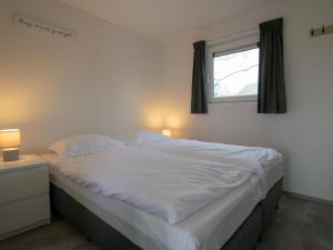 a bedroom with a large white bed with a window at De Zwaluw in Heiloo