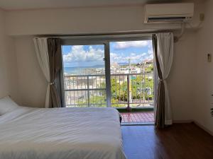 a bedroom with a bed and a large window at Prince Plage OKINAWA 6F in Fuzuchi +42 photos