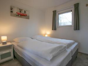 a bedroom with a bed with white sheets and a window at De Huismus in Heiloo