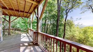 a wooden porch of a cabin with a view of the woods at Further Up & Further In in Topton