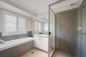 a bathroom with a shower and a tub and a sink at Hideaway -4BR Family Home with Pool, Near Beach in Caloundra
