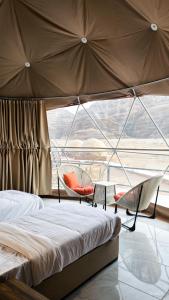 a bed and chairs in a room with a large window at Victoria Luxury camp in Wadi Rum