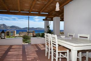 a white table and chairs on a patio with a view of the ocean at Pambelos Lodge - Apartments in Koufonisia