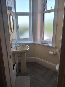 a bathroom with a sink and two windows at The Rising Sun in Rogerstone