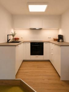 a kitchen with white cabinets and a black appliance at Geigenhof in Neudorf bei Ilz