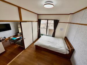a small room with a bed and a window at Stay Plus Azunoa in Oyama