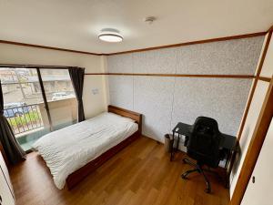 a bedroom with a bed and a desk with a camera at Stay Plus Azunoa in Oyama