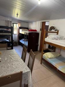 a room with a table and several bunk beds at Abrigo e Camping Recanto das Arvores in Itamonte