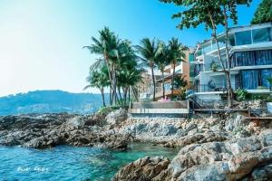 a hotel on the rocks next to the water at patong sunset villa Phuket in Patong Beach