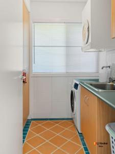a kitchen with a washing machine and a sink at Riverview Apartment 1.4 in Iluka